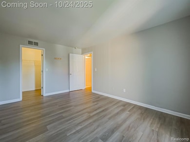 Unfurnished bedroom with a spacious closet and wood finished floors