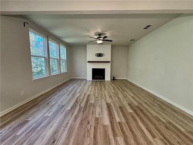 Unfurnished living room featuring a ceiling fan, a fireplace, and light wood-style floors