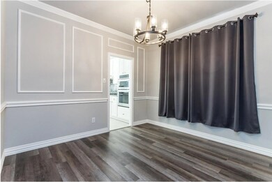 Unfurnished dining area with a chandelier, dark wood-style floors, crown molding, and a decorative wall