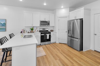 Kitchen featuring a breakfast bar, appliances with stainless steel finishes, a peninsula, white cabinets, and recessed lighting