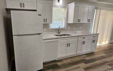 Kitchen with white appliances, dark wood-style flooring, light countertops, and white cabinetry