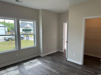 Unfurnished bedroom featuring visible vents, baseboards, dark wood finished floors, and a walk in closet
