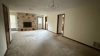 Unfurnished living room with carpet flooring, a fireplace, and a chandelier
