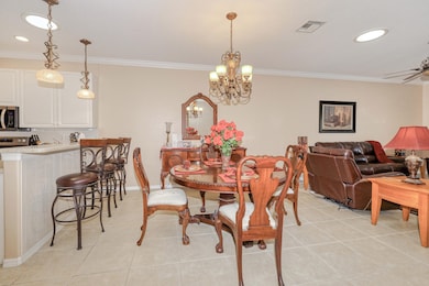 Dining area with crown molding, light tile patterned floors, a chandelier, and recessed lighting