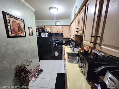 Kitchen with light tile patterned floors, black appliances, ornamental molding, backsplash, and light countertops