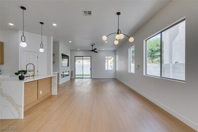 Kitchen featuring light countertops, ceiling fan with notable chandelier, pendant lighting, visible vents, and light wood-style flooring