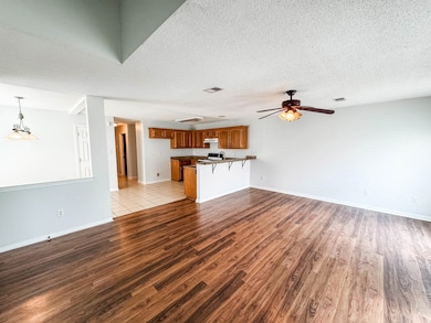 Unfurnished living room with wood finished floors, a ceiling fan, and a textured ceiling