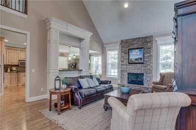Hardwood floors, a vaulted ceiling and the stacked stone fireplace create a warm and inviting living room open to the kitchen. Look at that fine woodworking framing the view to the kitchen!