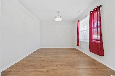 Unfurnished room with light wood finished floors and a chandelier