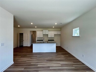 Kitchen with recessed lighting, white cabinetry, a kitchen island with sink, dark wood finished floors, and dark stone countertops
