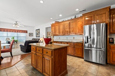 Kitchen with stainless steel fridge with ice dispenser, brown cabinetry, backsplash, a kitchen island, and recessed lighting