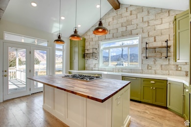 Kitchen featuring green cabinets, wood counters, a center island, light wood-type flooring, and decorative backsplash