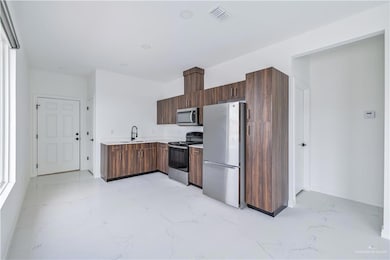 Kitchen featuring light marble finish floors, stainless steel appliances, light countertops, and modern cabinets