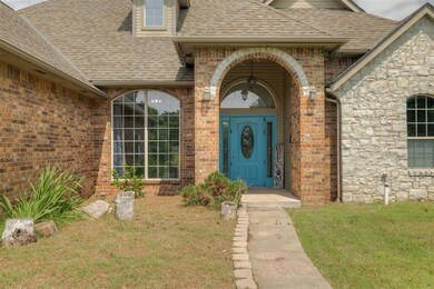 Property entrance featuring a shingled roof, brick siding, and a yard