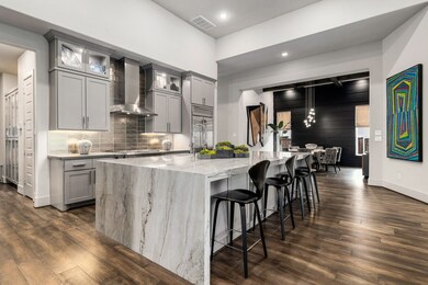 Entertainer's paradise with a seamless open floor plan. The kitchen island with a luxurious waterfall countertop serves as the focal point, offering both seating and prep space. This space perfectly blends high-end design with functional living.