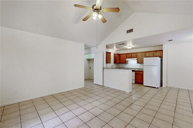 Kitchen featuring brown cabinets, high vaulted ceiling, freestanding refrigerator, open floor plan, and a ceiling fan