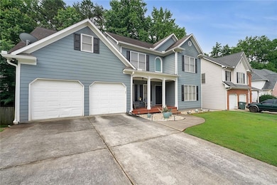 Traditional-style house featuring covered porch, driveway, a front yard, and an attached garage
