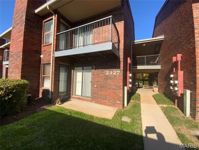 Back of house with a balcony, brick siding, and a lawn