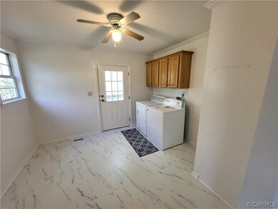 Clothes washing area with a wealth of natural light, washing machine and clothes dryer, cabinets, and light tile floors