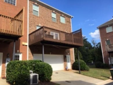 Back of property with central AC, a garage, concrete driveway, a balcony, and brick siding