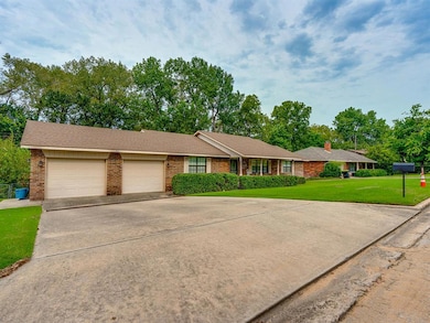 Ranch-style house featuring driveway, a front lawn, brick siding, and an attached garage