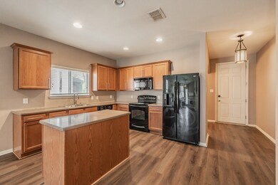 Kitchen with black appliances, light countertops, dark wood-style floors, recessed lighting, and pendant lighting