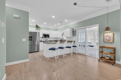 Kitchen with white cabinetry, a breakfast bar, lig