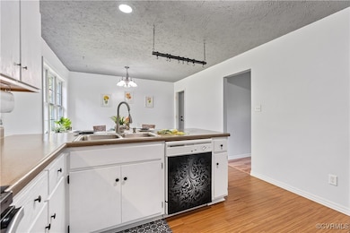 Kitchen with white cabinetry, dishwasher, sink, pe