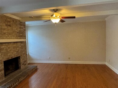 Unfurnished living room featuring wood finished floors, crown molding, a brick fireplace, and a ceiling fan
