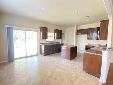 Kitchen featuring black dishwasher, a center island, light stone countertops, sink, and light tile floors