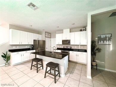 Kitchen with dark countertops, white cabinetry, li