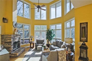 The Great Room features a wall of windows to allow enjoyment of the views and lets the natural light shine in. This room also has hardwood floors, a cathedral ceiling, and a wood burning fireplace.