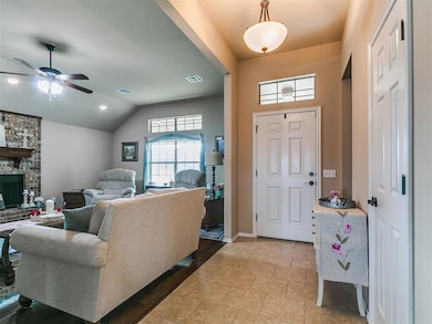 Foyer entrance featuring lofted ceiling, a fireplace, and a ceiling fan