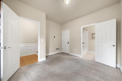 Unfurnished bedroom with carpet floors, connected bathroom, and baseboards