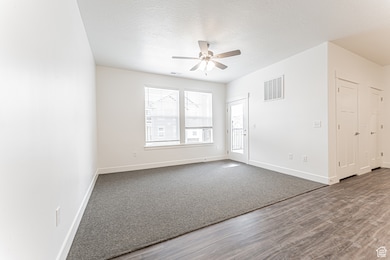 Spare room with baseboards, ceiling fan, dark wood-style flooring, and a textured ceiling