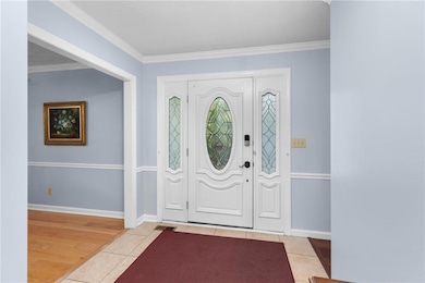 Entryway with light tile patterned floors and crown molding