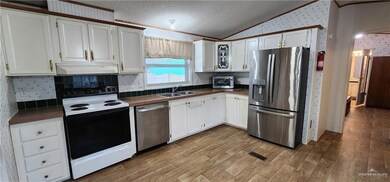 Kitchen with lofted ceiling, white cabinetry, a textured ceiling, and appliances with stainless steel finishes