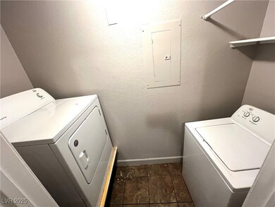 Laundry area featuring independent washer and dryer, electric panel, a textured wall, and dark tile patterned floors