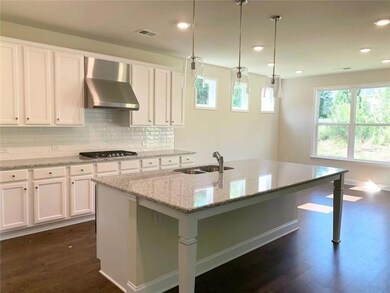Kitchen with tasteful backsplash, wall chimney range hood, light stone counters, hanging light fixtures, and recessed lighting