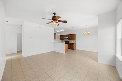 Unfurnished living room with a chandelier, a ceiling fan, and light tile patterned floors