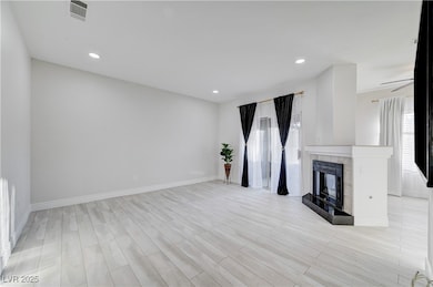Unfurnished living room featuring plenty of natural light, recessed lighting, a high end fireplace, and light wood-style floors