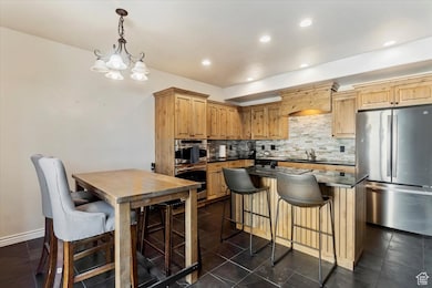 Kitchen featuring stainless steel appliances, backsplash, a breakfast bar, a center island, and pendant lighting