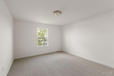 Empty room with light colored carpet and baseboards