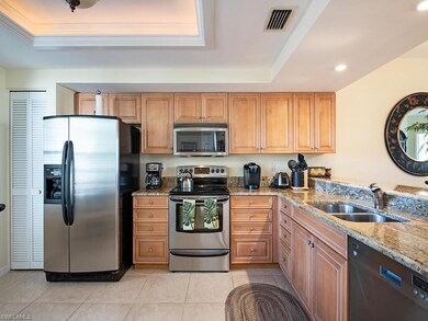Kitchen with stainless steel appliances, a tray ceiling, sink, light stone countertops, and light tile patterned flooring