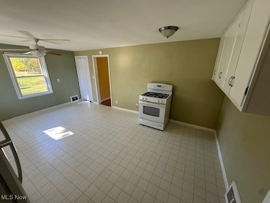 Kitchen with white cabinetry, white gas stove, ceiling fan, and light countertops