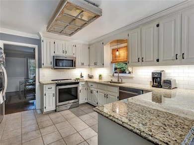 Updated kitchen with classic white cabinetry (real wood, not particle pressboard), granite counters, classic subway tile backsplash with under cabinet task  lighting, tile floor, stainless appliances.