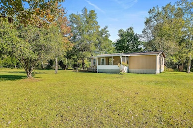 Rear view of property with a yard and view of wooded area