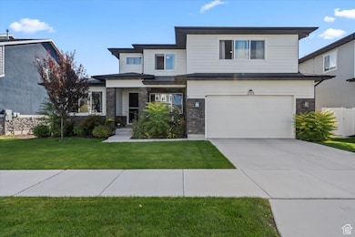 View of front facade featuring a front lawn, driveway, a garage, and stone siding