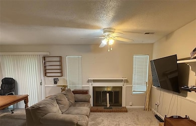 Living room with carpet, ceiling fan, and a brick fireplace
