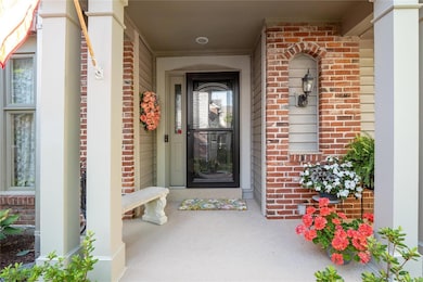 The covered front porch and beautiful gardens surr